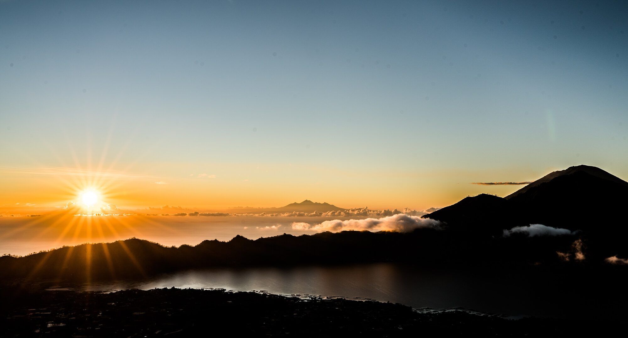 Sunrise seen from Mount Batur, with Lake Batur below and mountains in the distance