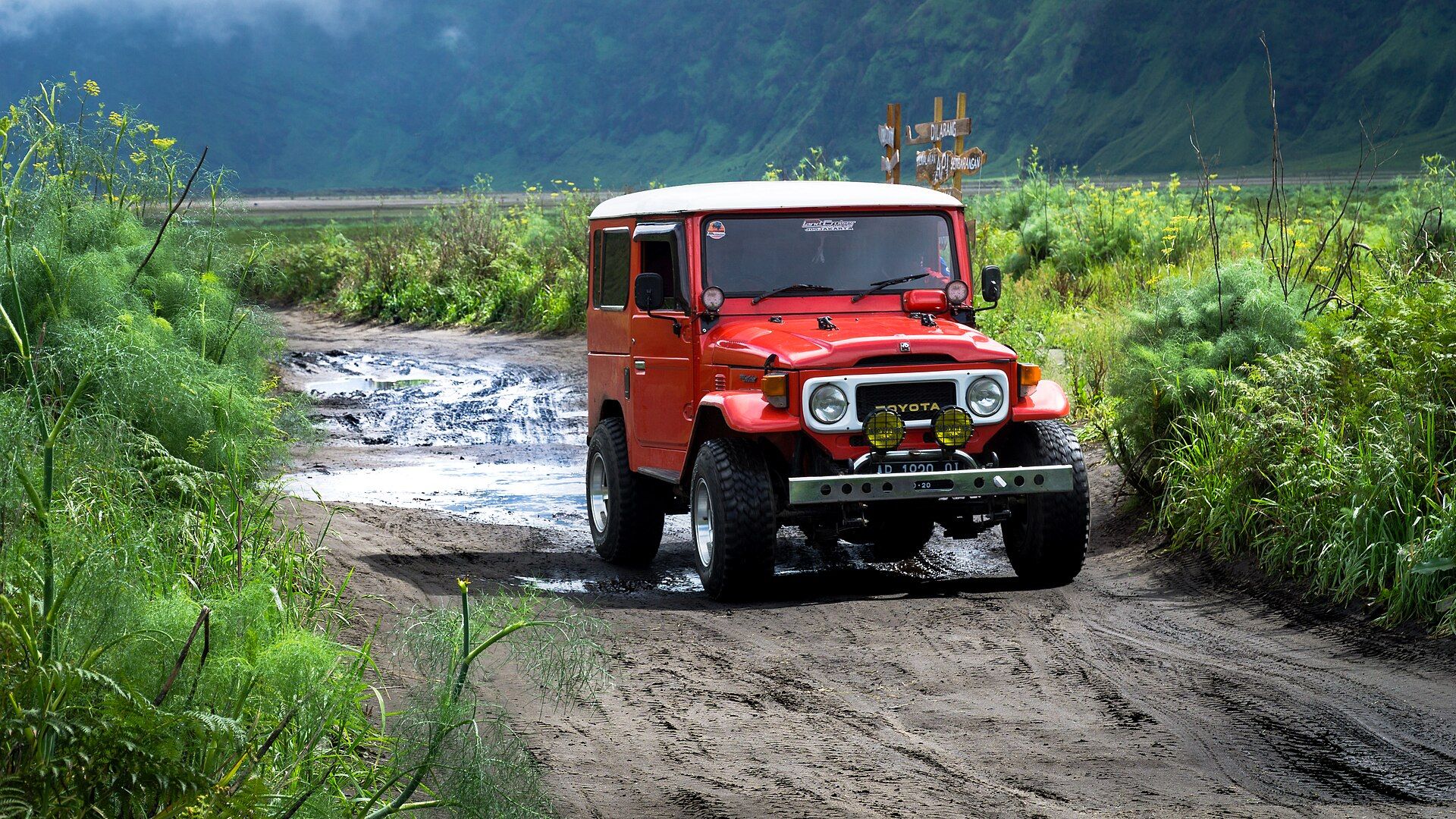 Illustrative photo taken on Mount Bromo in East Java, not Mount Batur. A red 4WD jeep on a wet volcanic track