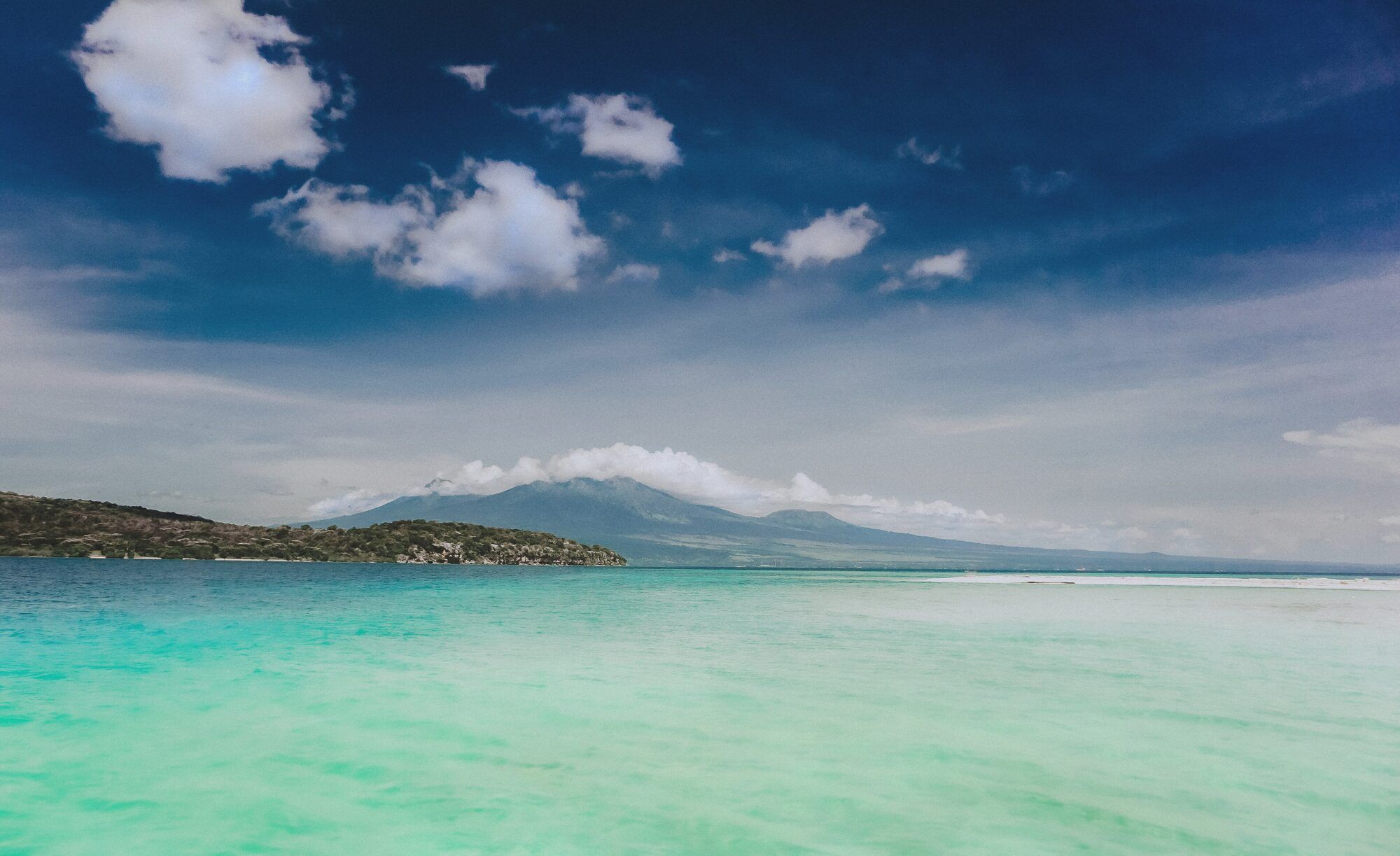 Clear turquoise water off Menjangan Island, with the coast and hills behind