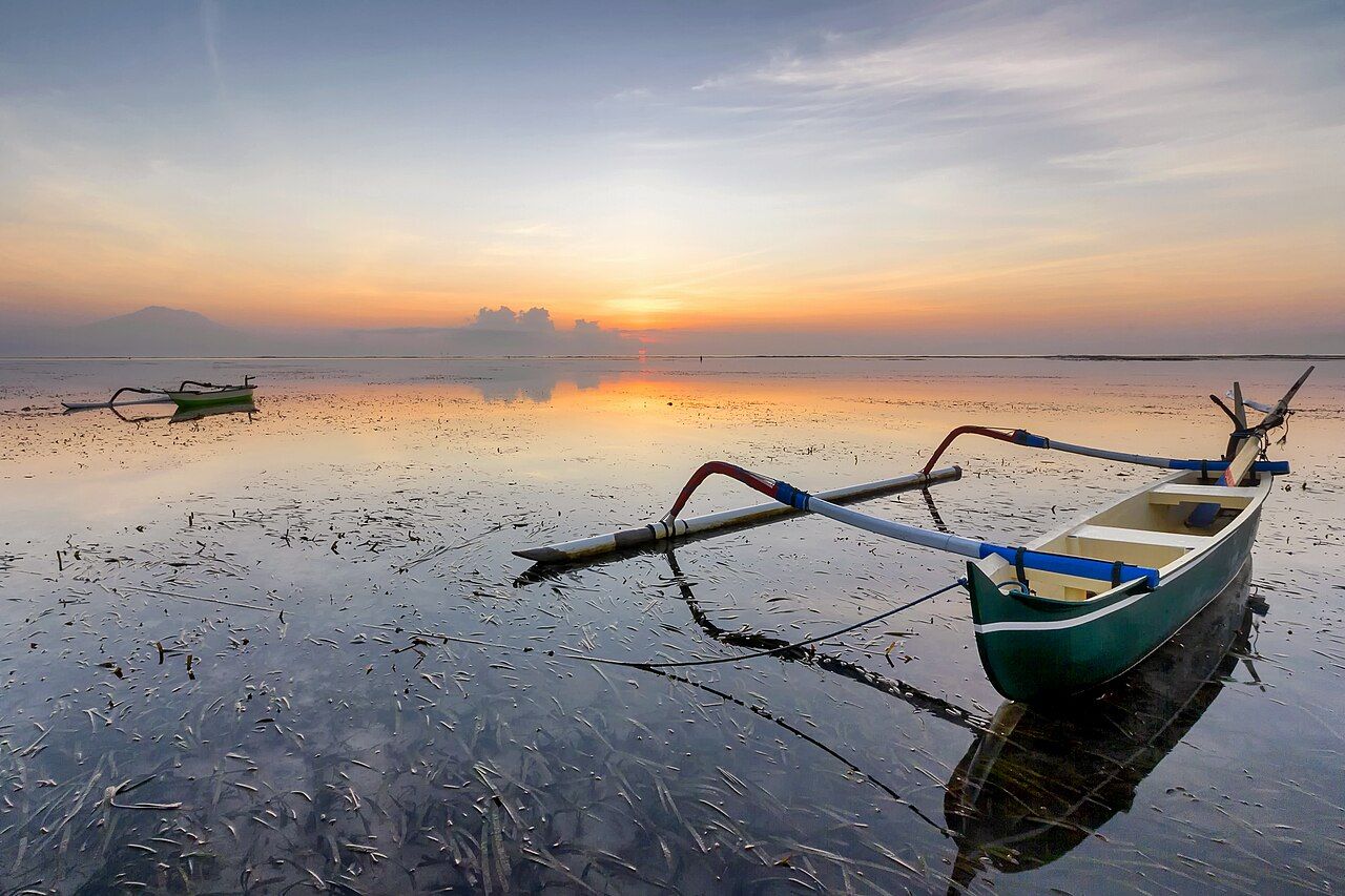Traditional outrigger boats with coloured sails at sunrise in Sanur
